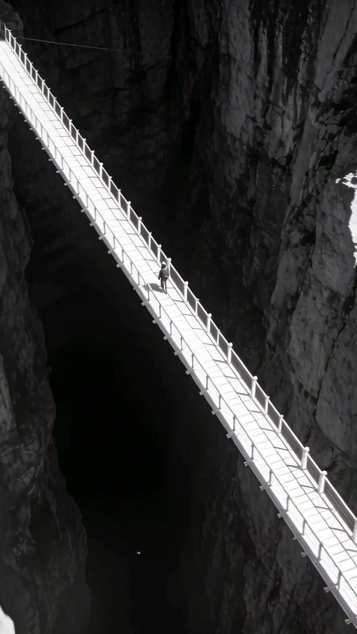 Video verticale: Escursionista che cammina attraversando una stretta passerella su una gola per attraversare il canyon, regolando lo zaino.