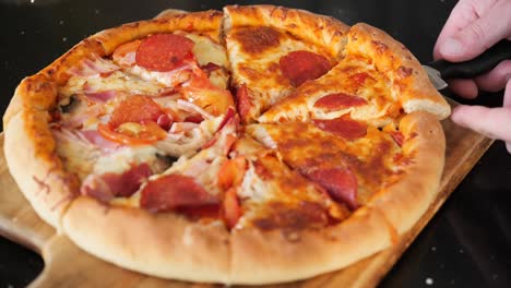 primer plano de cámara lenta de tomar un trozo de pizza de una cáscara de pizza de madera