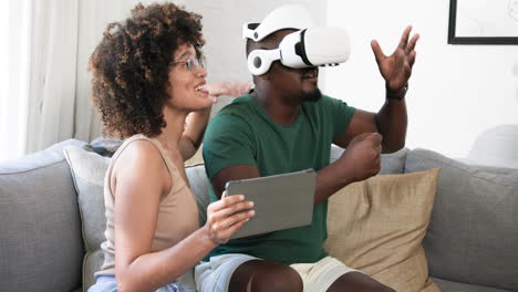 on couch, diverse friends using vr headset, woman with tablet, laughing together, at home