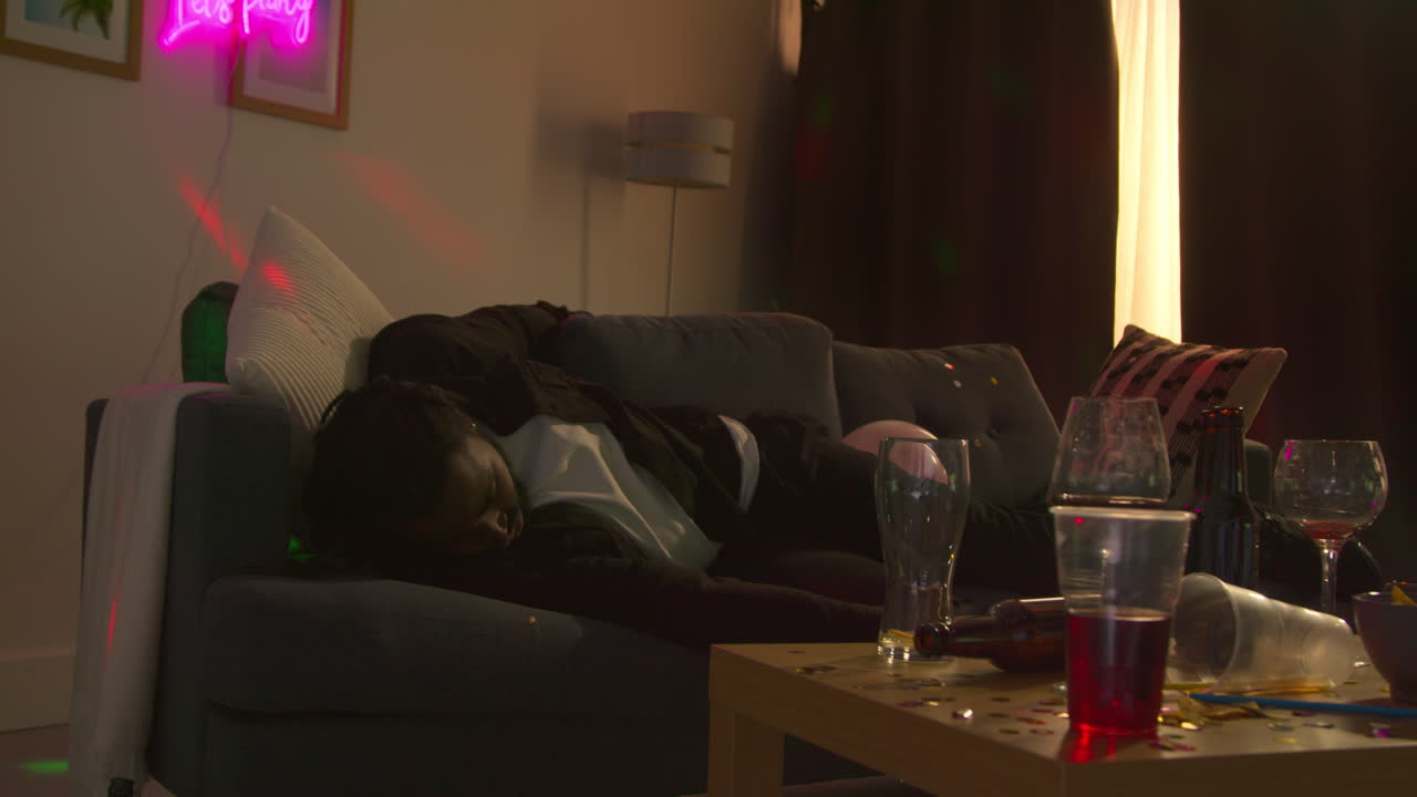 Man Lying On Sofa Recovering From Drinking Alcohol At House Party Suffering With Hangover