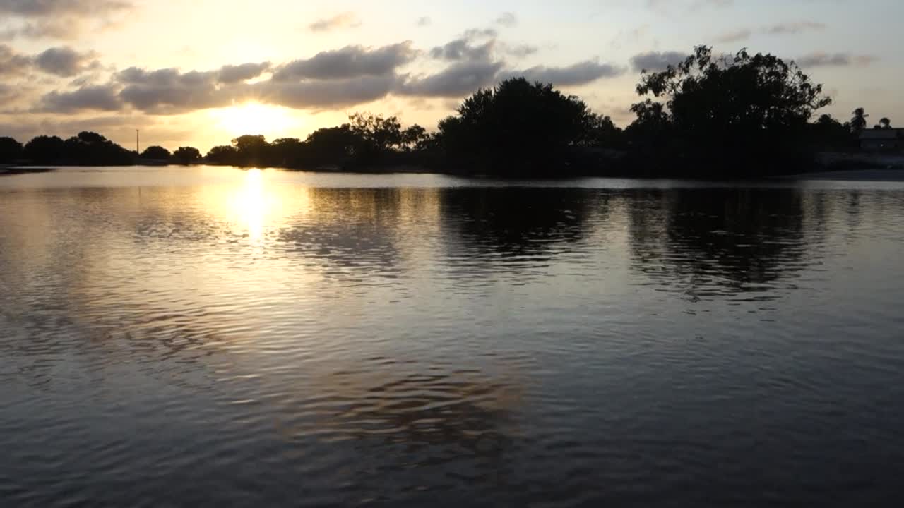 um belo pôr do sol perto de um lago com nuvens no céu, tiro largo estático