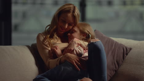 mother hugging daughter on couch. mom and child spending time together at home.