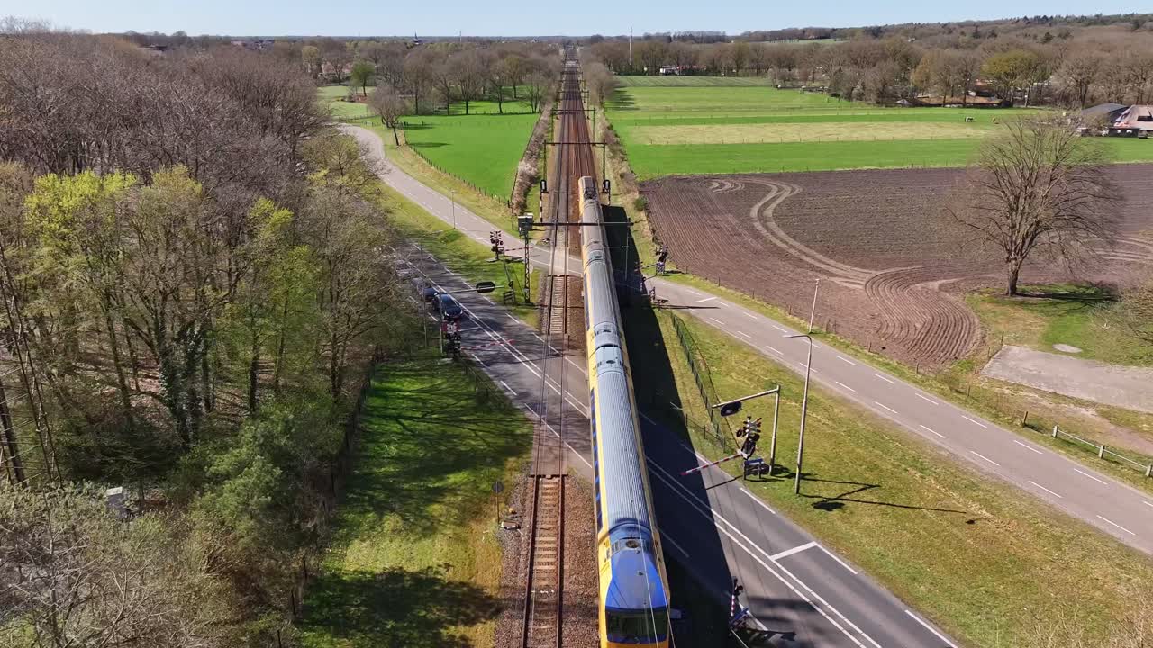 Aerial Tracking Shot of Train as it Cruises Down Railroad Tracks During the Daytime Through a Forest and Field