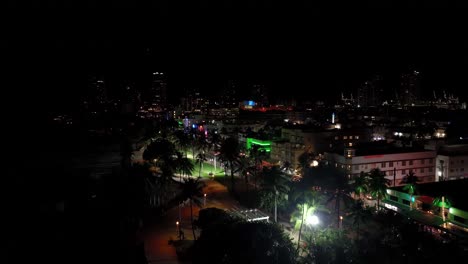 imágenes aéreas nocturnas de drones de miami, estados unidos, movimiento hacia adelante que muestra muchas luces de diferentes colores sobre los edificios, junto con palmeras