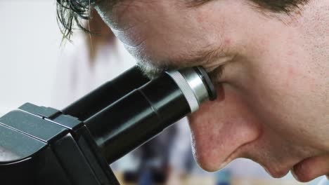 man in lab coat looking into a microsope