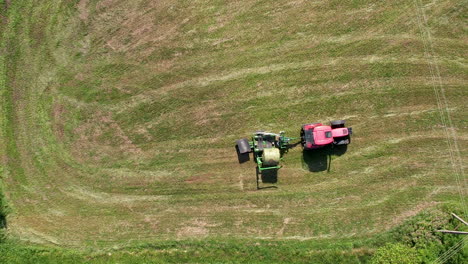 Tractor-Recogiendo-Pacas-De-Heno-En-El-Campo---Antena-Arriba-Hacia-Abajo