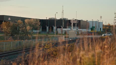 cars driving over train station railway crossing tracks in industrial urban city with golden hour morning sunrise and radio towers in distance cinematic toronto ontario markham ttc cinematic prores 4k