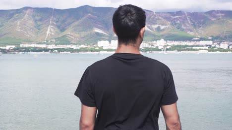 man overlooking the ocean and mountains