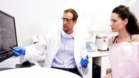 Dentista-Mostrando-Una-Radiografía-De-Los-Dientes-A-Una-Paciente-En-La-Computadora