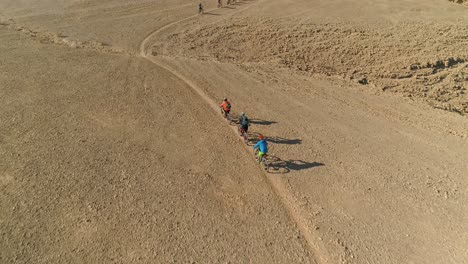 aerial footage of a group of bicycle riders riding on bike trails in the desert