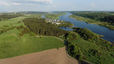 pedestrian pathway winding through lithuanian flatlands near majestic river, aerial view