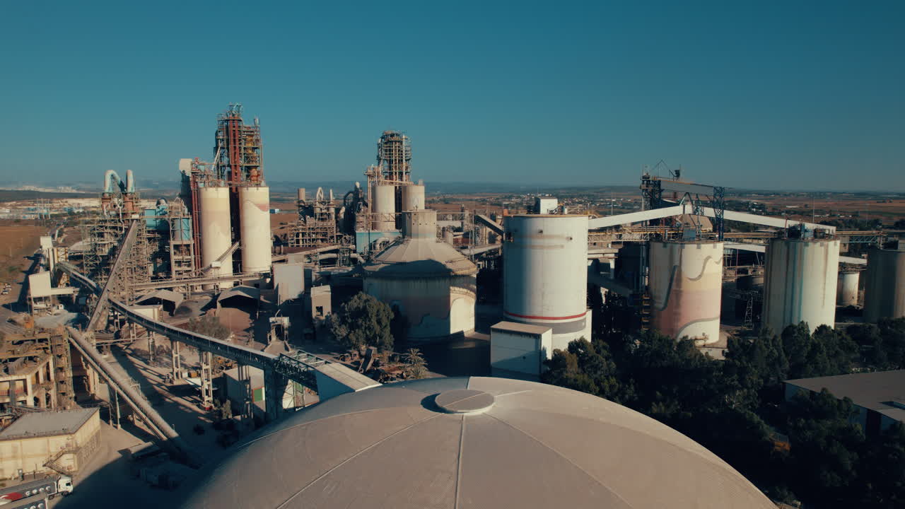 Aerial shot of a huge cement factory, innovative industrial area with lots of hangars and trucks, beautiful area with trees, parallax shot-1