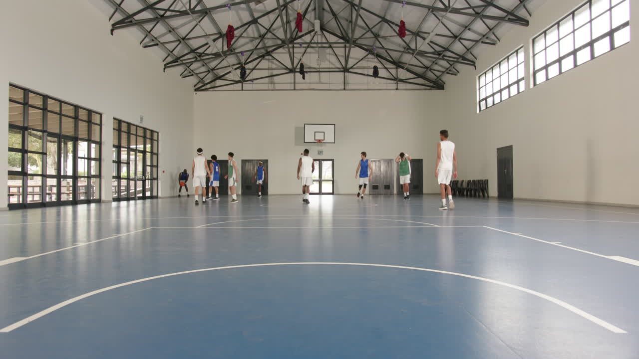 Basketball players practicing in gym, passing ball and running energetically