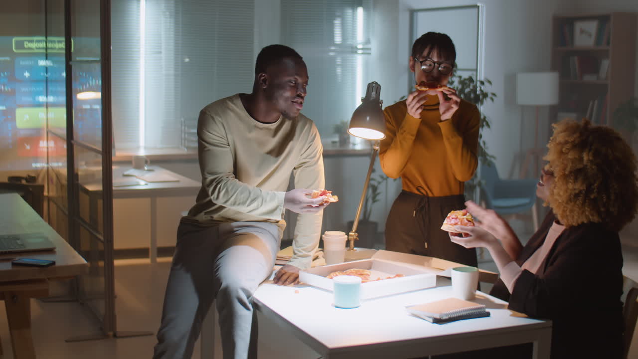 Diverse Colleagues Eating Pizza in Office at Night
