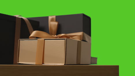 Close-Up-Of-Gift-Wrapped-Present-Decorated-With-Ribbon-On-Table-Shot-Against-Green-Screen-3