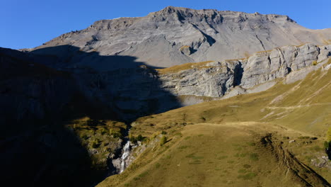 waterfall flowing into la tieche valley on a sunny day with les faverges summit in background in valais, switzerland