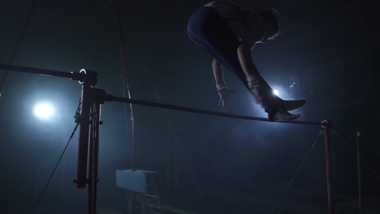 ginnasta su uno sfondo scuro sulla barra trasversale esegue giri e salti sopra se stesso in aria in slow motion e intorno al fumo