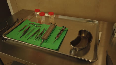 Toma-Panorámica-De-Suministros-Médicos-En-Una-Mesa-De-Acero-Inoxidable-En-La-Morgue