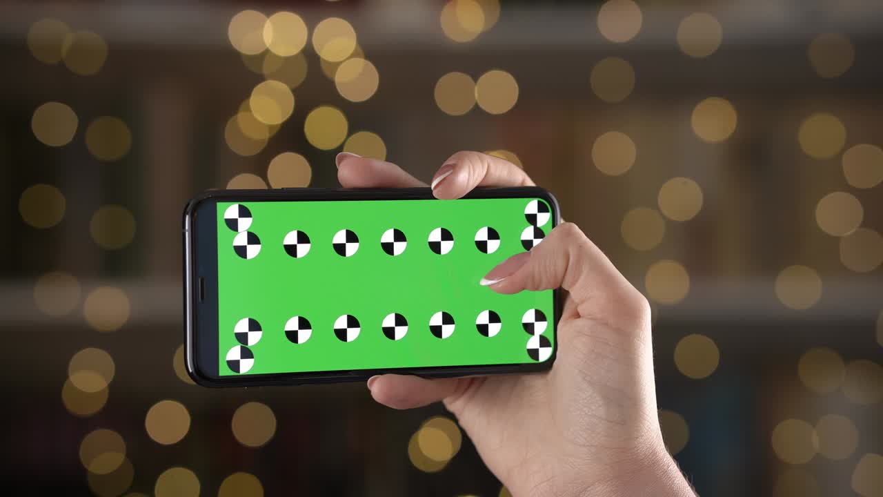 móvil en orientación horizontal con marcadores de seguimiento en la mano de la mujer contra el fondo bokeh