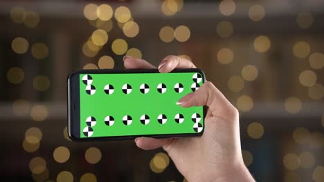 móvil en orientación horizontal con marcadores de seguimiento en la mano de la mujer contra el fondo bokeh