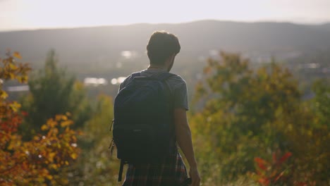 Photographer-arrives-at-the-top-of-a-mountain-to-take-a-picture-of-the-sunset-over-a-valley