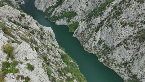 lake komani with steep rocky cliffs surrounding clear water, aerial view
