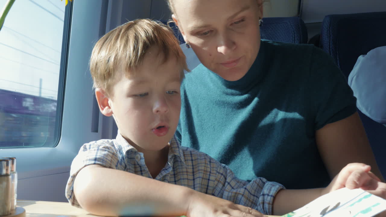 hijo y madre con libro ilustrado en el tren