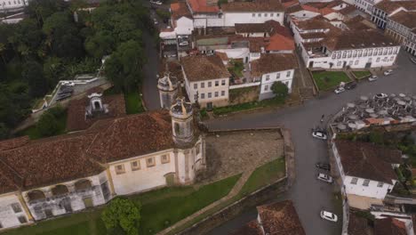 aerial rotating pan showing the fransisco of assisi church in ouro preto, brazil, zooming out revealing the surrounding neighbourhood with typical colonial architecture and tourist market