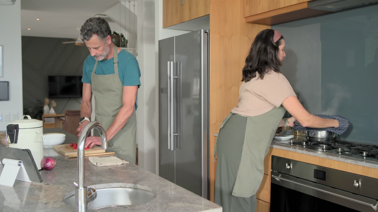 Video verticale: Partner in cucina che mescola, poi solleva la pentola e scola la pasta mentre un uomo taglia
