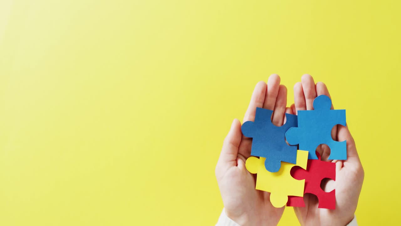 video de manos sosteniendo piezas de rompecabezas en fondo amarillo con espacio de copia