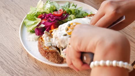 person eating a delicious breakfast sandwich with salad