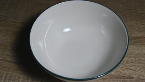 ceramic white bowl on the table zoomed in before it is filled with some cereals or granola during breakfast