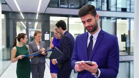 hombre de negocios usando una tableta digital mientras los hombres de negocios discuten en segundo plano