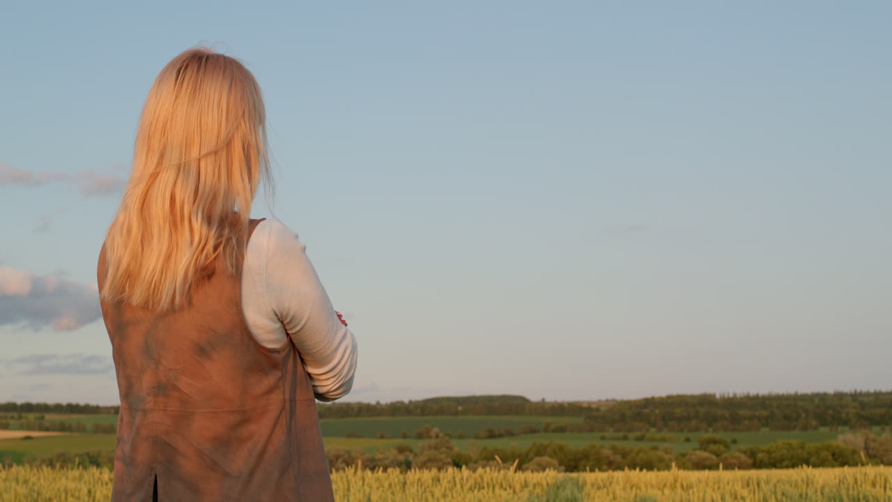한 여자 가 밀 을 고 있는 그림 같은 풍경 을 바라보고 있다.