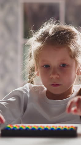 upset little girl student plays with toy abacus learning mental arithmetics at table in kindergarten classroom close view slow motion