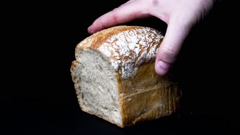 light-bread-is-put-down-by-hand-in-front-of-black-background-slow-motion