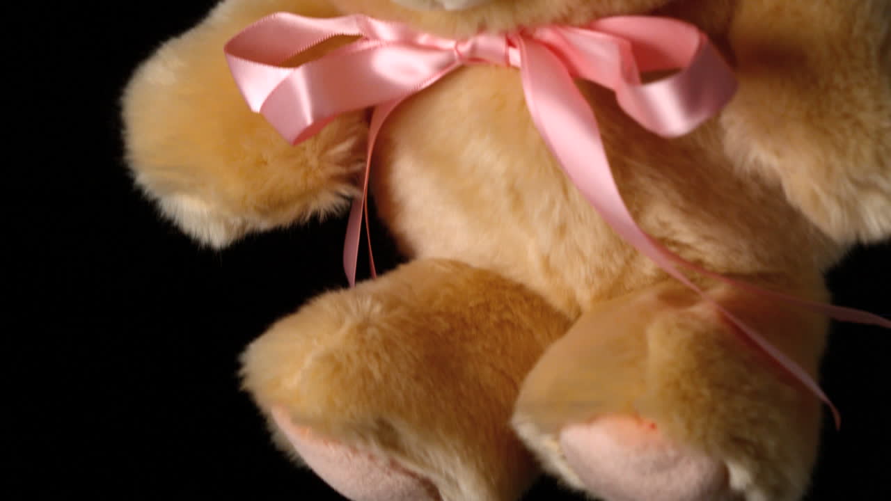 귀여운 테디 베어가 검은 바탕에 가까이 떨어집니다.