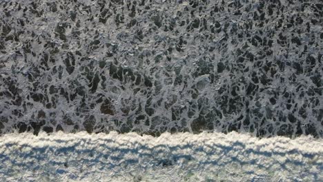 a top down shot of waves moving across the screen, with beautiful patterns in the swell of the wave