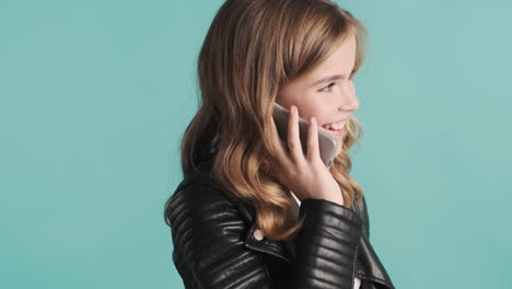 una adolescente caucásica con chaqueta de cuero hablando por teléfono.
