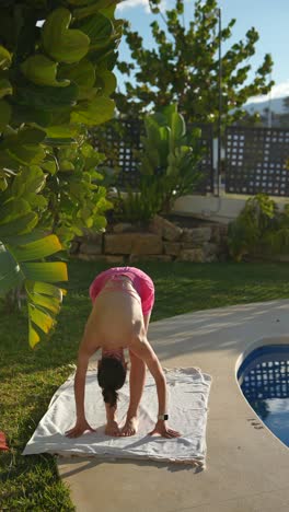 woman practicing yoga outdoors by a pool