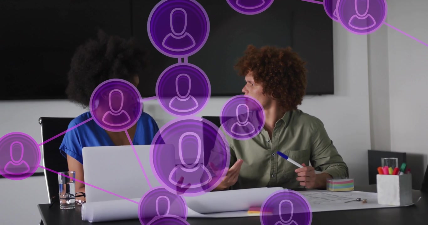 coworkers glancing laptop and starting network icons linking tech nodes while pointing blueprint