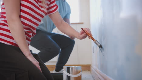 Close-Up-Of-Couple-Decorating-Room-In-New-Home-Painting-Wall-Together