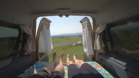 nomadic couple lying down moving their feet in unison inside a camper van