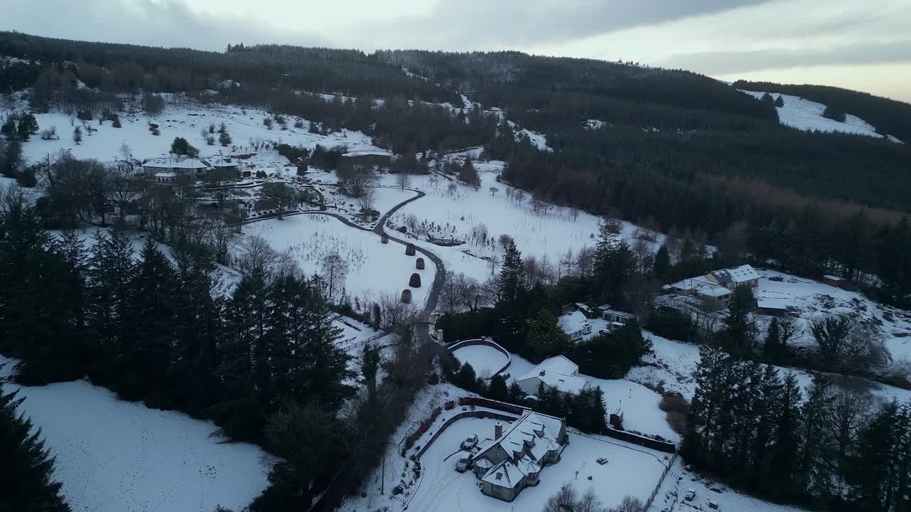 Aerial view of a mountain village with few house surrounded by Pine trees during snow storm and winter season in Ireland. Dublin Mountains - Ireland
