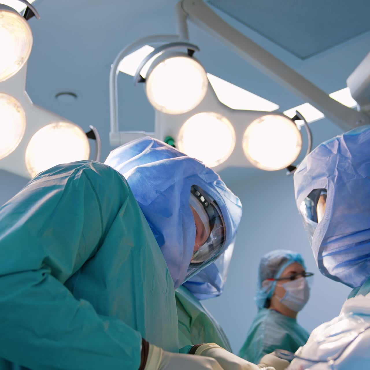 Group of surgeons working at arthroscopic surgery. Male doctors in protective helmets treating trauma