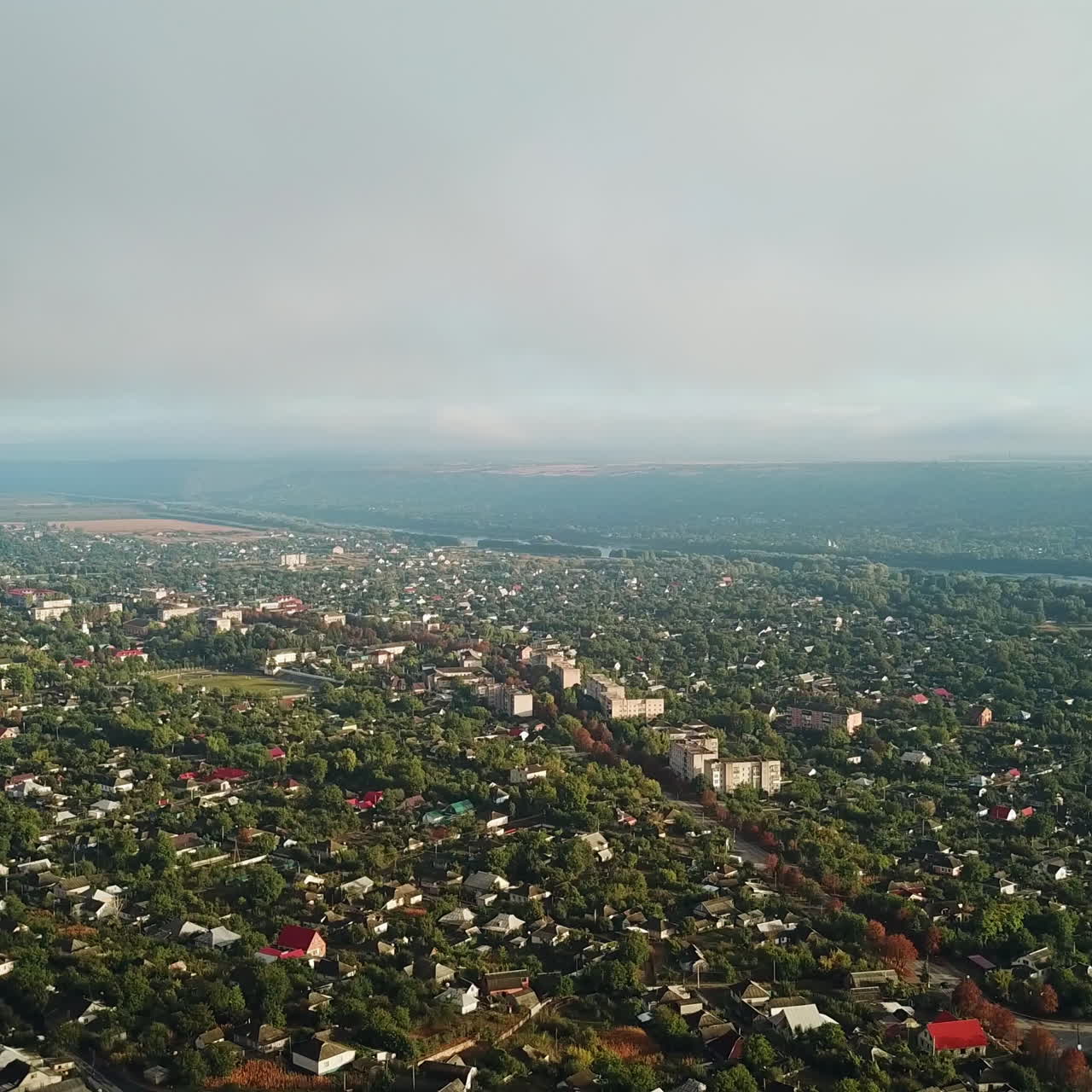 Unbelievable view of a big town nearthe river and green trees in the morning. Aerial filming of beautiful landscape in summer. Motion from the bottom to top