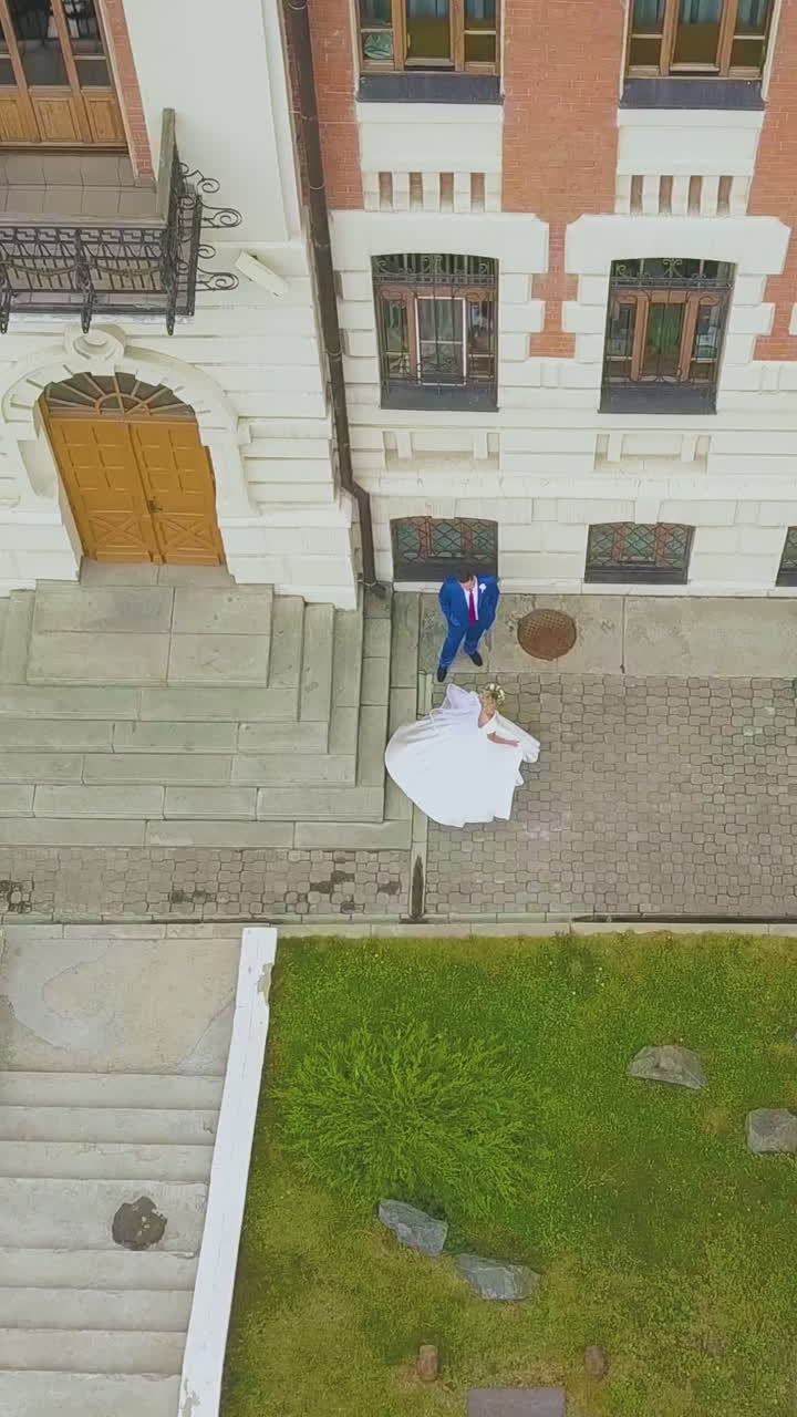 beautiful bride dances near happy groom near beautiful restored building in sunny street on autumn day bird eye view