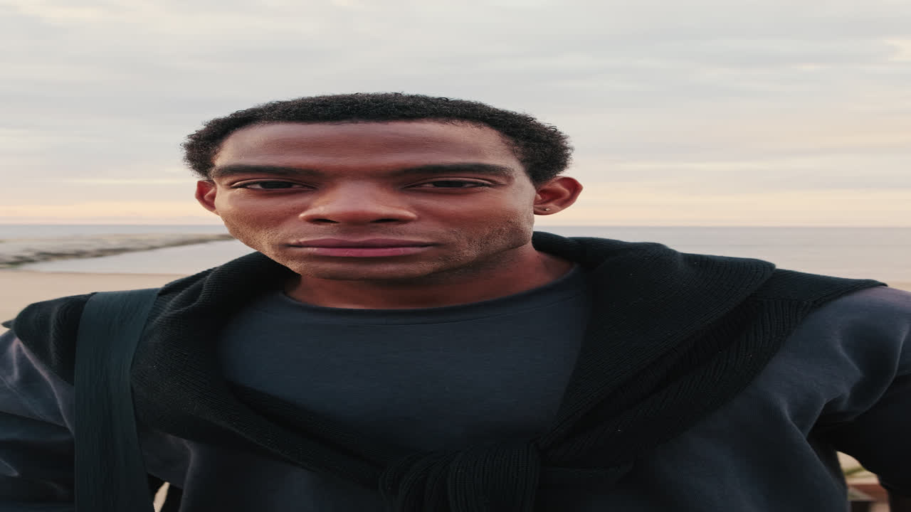 Young Black Man Blinking and Looking at Camera on Beach