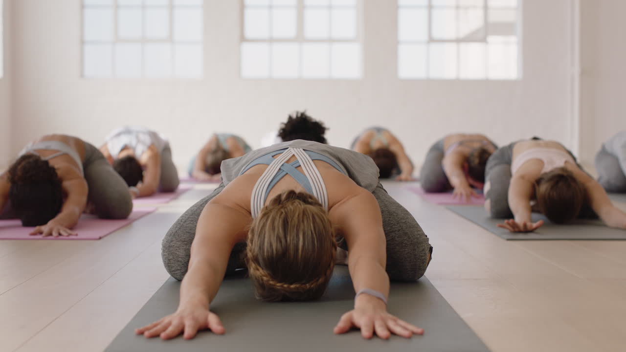 attraente istruttore di lezioni di yoga che guida la meditazione di gruppo insegnando a donne sane i bambini posano godendosi l'esercizio in palestra praticando la postura all'alba