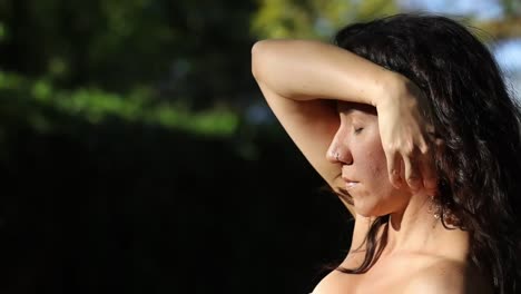 Close up of woman in park playing with her dark brown hair. Handheld